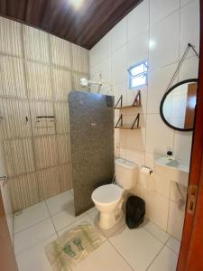 a bathroom with a toilet and a sink and a mirror at Lotus Beach in Piaçabuçu +11 photos