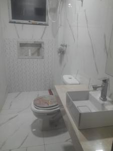 a white bathroom with a toilet and a sink at Guimarães in Viçosa