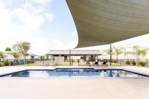 a swimming pool with a building in the background at Riverside Cabin Park in Shepparton