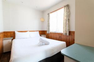 a bedroom with a white bed and a window at Riverside Cabin Park in Shepparton +51 photos