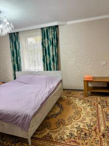 a bedroom with a bed and a window and a rug at Green yard Guest house Barskoon in Barskoon