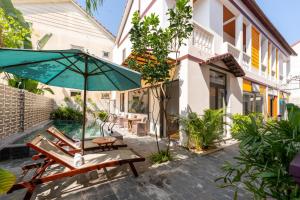 a patio with chairs and an umbrella and a pool at Laughter Garden villas in Tân Thành (1)