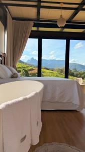 a bedroom with a large white bed with a view at Morada do Valle Chalés in Timbe do Sul