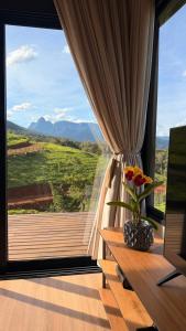 a room with a window with a vase of flowers on a table at Morada do Valle Chalés in Timbe do Sul +4 photos
