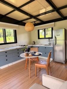 a kitchen with a table and a refrigerator at Morada do Valle Chalés in Timbe do Sul