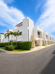 a white building with palm trees on the side of a road at Modern Villa 2 BR Near Airport, Beaches, Dining in Punta Cana