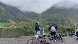 two people standing next to their bikes on a mountain at Crater Eruption Backpacker Hostel in Baños