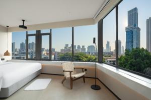 a bedroom with a bed and a chair and large windows at SOVIS PLUS HOTEL in Shenzhen +61 photos