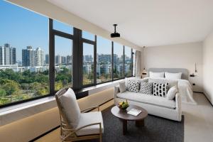 a living room with a couch and chairs and large windows at SOVIS PLUS HOTEL in Shenzhen