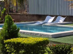 a swimming pool with white chairs in a yard at Lodge Ayla Punta Mango in Jucuarán