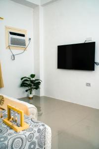 a living room with a couch and a tv on a wall at Casa Marelle in Lapu Lapu City