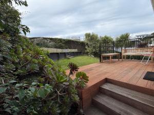 a backyard with a wooden deck with a bench on it at Tyne above Town in Oamaru
