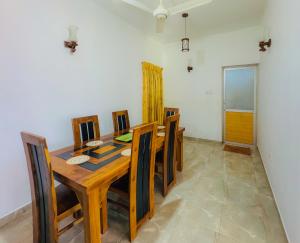 a dining room with a wooden table and chairs at Senu Bungalow in Ragama