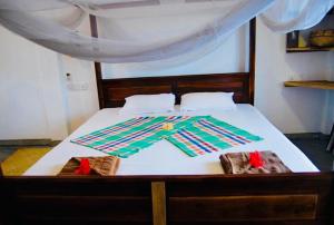 a bedroom with a bed with white sheets at Cili Hotel & Pizza Restaurant in Arugam Bay