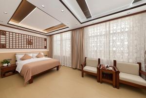 a bedroom with a bed and two chairs and a window at Dali Classical Rosewood Boutique Inn in Dali