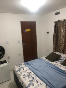 a bedroom with a bed with a blue blanket and a door at Pousada da Neném - Quarto Tangerina in Campina Grande