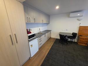 a kitchen with white cabinets and a table at Waikato Hospital Motel in Hamilton