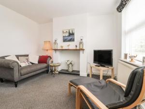 a living room with a couch and a tv at Bluebell Cottage in Selby