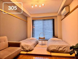 a room with two beds and a window at ura 東横のヨコ in Okayama