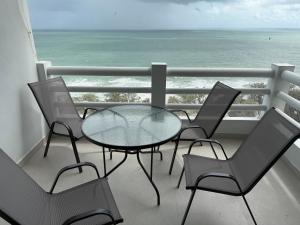 a glass table and chairs on a balcony with the ocean at New world condo1802 in Rayong