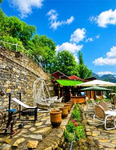 a stone patio with chairs and a swing at Escape Retreat Hunza in Karimabad Hunza