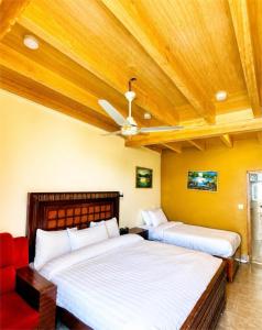 two beds in a room with a ceiling fan at Escape Retreat Hunza in Karimabad Hunza