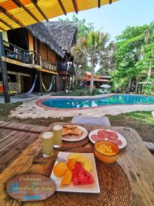 a table with plates of food and drinks and a pool at Mar Villa Eco Lodge Surf & Kite Perla Marina by Encuentro Beach in Sosúa