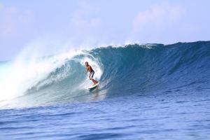 Ein Mann reitet eine Welle auf einem Surfbrett im Ozean in der Unterkunft Rock Pool Homestay in Huu