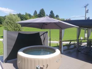a hot tub with an umbrella on a patio at Apartma Dečko Rogaška in Rogaška Slatina