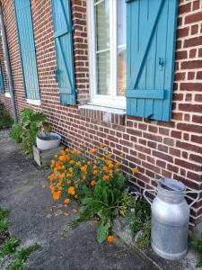 a brick building with a blue window and flowers at Chez Lullu in Saint-Quentin-Lamotte-Croix-au-Bailly +6 photos