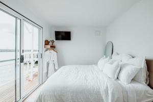 a white bedroom with a large bed with white pillows at The Floathouse - Floating tiny home on the Murray in White Sands