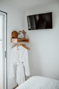 a white robe hanging on a wall next to a bed at The Floathouse - Floating tiny home on the Murray in White Sands