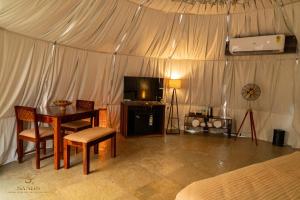 a room with a table and a television in a tent at Sands - Tajpur in Tajpur