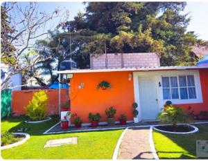 an orange house with a white door in a yard at Posada del Jardín in Huasca de Ocampo