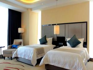 a hotel room with two beds and a chair at Pacific Regency Hotel Shenyang in Shenyang