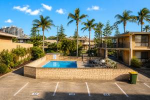 an empty parking lot with a pool and palm trees at Forster Motor Inn in Forster