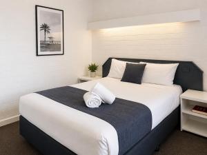 a bedroom with a large bed with white sheets at Forster Motor Inn in Forster +24 photos