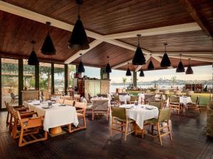 a restaurant with white tables and chairs and windows at Aliée Istanbul - A Paris Society Collection Hotel in Istanbul