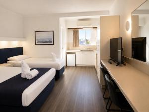 a hotel room with two beds and a flat screen tv at Forster Motor Inn in Forster
