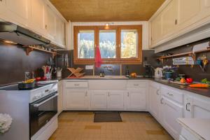 a kitchen with white cabinets and a window at MontBlanc Alpine Ski & Sauna Retreat - Happy Rentals in Le Tour