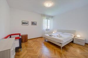 a white bedroom with a bed and a wooden floor at Margherita near lake - Family Friendly - Happy Rentals in Toscolano Maderno