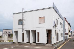 a white building with a ladder on the side of it at Furano Ezo Murasaki B in Furano