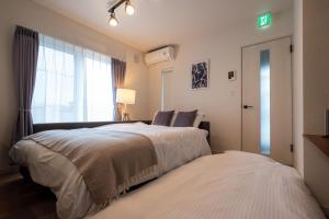 a bedroom with two beds and a window at Furano Ezo Murasaki B in Furano