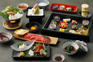 a table topped with different types of food on trays at Gion Ryokan Karaku in Kyoto