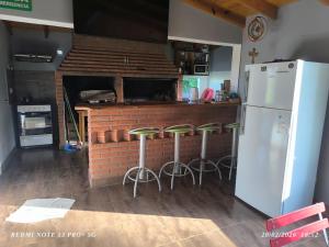 a kitchen with a bar with stools and a refrigerator at Alojamiento Amado in Los Antiguos