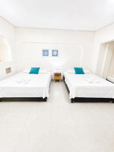 two beds in a room with white walls at Apartasuite tolu in Tolú +14 photos
