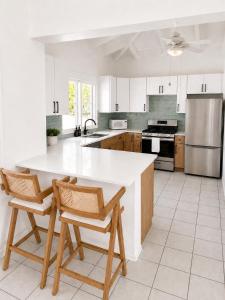 a kitchen with a large white counter and chairs at The View at Green Cay - Full AC - Walk to the Beach in Christiansted