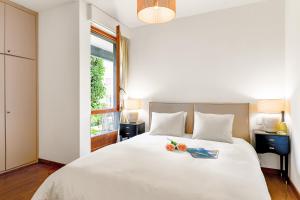 a white bed with a bowl of fruit on it at Casa Rinetta with Patio and A/C - Happy Rentals in Lugano