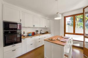 a kitchen with white cabinets and a wooden counter top at Casa Rinetta with Patio and A/C - Happy Rentals in Lugano