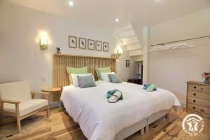 a bedroom with a large white bed and a chair at Le murmure des oiseaux in Plussulien